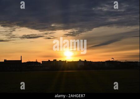 Vista dall'ex aeroporto Tempelhof nel centro di Berlino per la case ombreggiato sul bordo del campo di aviazione nel sole di setting. Foto Stock