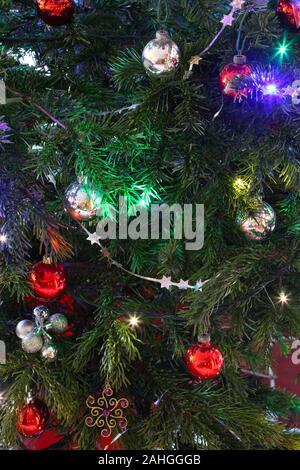 Decorazioni su albero di Natale, baubles, tinsel e luci in close-up. Foto Stock