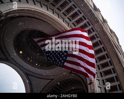 La neve cade intorno alla bandiera americana su una giornata invernale Foto Stock