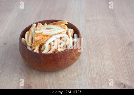 Arancia candita in ciotola di legno sullo sfondo di legno Foto Stock