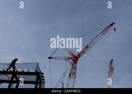 Operai davanti alle gru presso il cantiere per il nuovo stadio principale per le Olimpiadi di Tokyo 2020 a Gaiemmae, Tokyo, Giappone Foto Stock