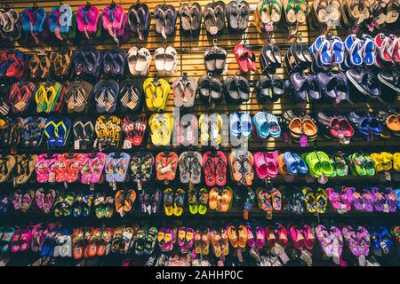 Phuket, Tailandia - 10 Dicembre 2018 : tante pantofole con molti design come logo o di un cartone animato in esso sono appesi alla parete in un negozio Foto Stock
