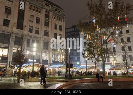 Budapest, Ungheria Mercatino di Natale con la folla in Piazza Vorosmarty. Vista notturna di decorazioni di festa al tradizionale cibo stagionale e il vino si spegne. Foto Stock