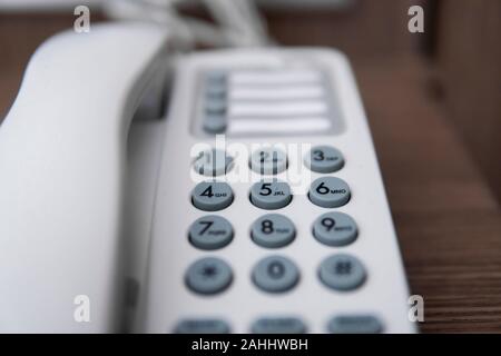 Vintage bianco telefono con battoms grigio su un tavolo marrone in hotel. Foto Stock
