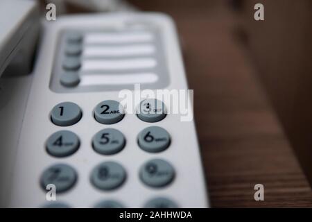 Vintage bianco telefono con battoms grigio su un tavolo marrone in hotel. Foto Stock