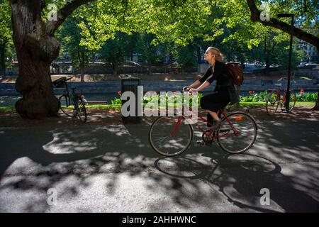 Donna su una bicicletta su una passeggiata sulle rive del fiume Aura in Turku Finlandia. Foto Stock