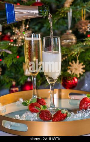 Champagne versato in bicchieri con le fragole su sfondo di festa Foto Stock