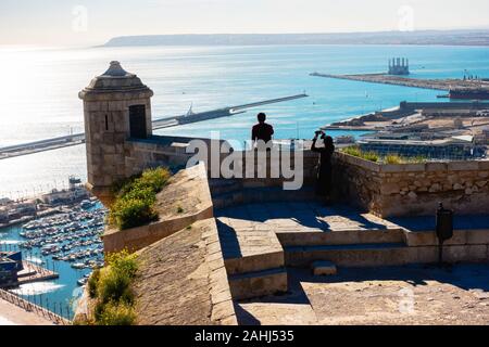 Alicante, Spagna - 23 dicembre 2019: turistici guardando cityscape e rendendo le foto mobile sulla parte superiore della torre del castello di Santa Barbara, Alicante Spagna Foto Stock