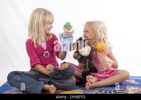 Zwei Mädchen bionda, 6 und 7 Jahre alt, spielen mit Handpuppen, Kasperle, Figuren, teatro, Freunde, Geschwister, Kasperletheater, signor:Sì Foto Stock