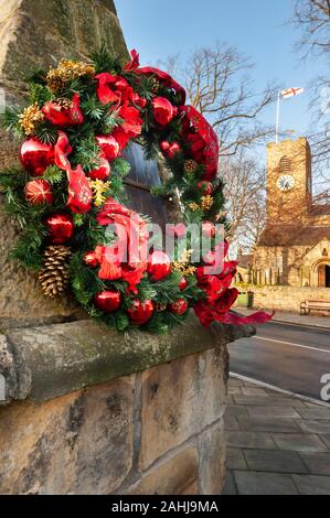 Ghirlanda di Natale decorazione in Northumberland villaggio di Corbridge con la chiesa parrocchiale in background Foto Stock