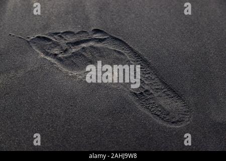 Soft Smooth Black texture di sabbia sulla spiaggia con ghiaia poco sparsi, hanno una grande impronta di umano su Centro Foto Stock
