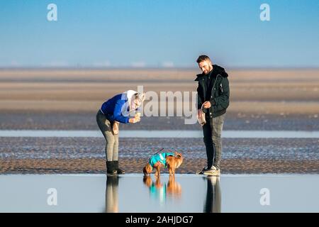 Southport, Merseyside, 30 dicembre 2019. La gente fuori di testa per un po' di divertimento al sole con i loro cani sulla spiaggia di Southport nel Merseyside. Il sole e cieli blu ha salutato i visitatori della località balneare come il mite inverno condizioni meteo continuare durante le vacanze di Natale. Credito: Cernan Elias/Alamy Live News Foto Stock