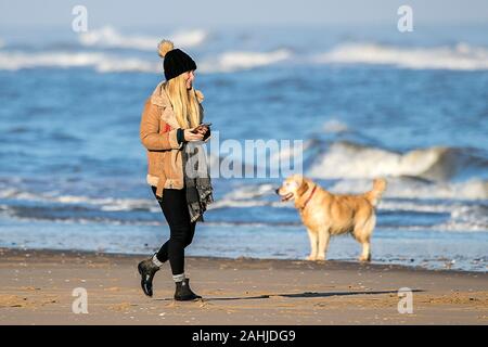 Southport, Merseyside, 30 dicembre 2019. La gente fuori di testa per un po' di divertimento al sole con i loro cani sulla spiaggia di Southport nel Merseyside. Il sole e cieli blu ha salutato i visitatori della località balneare come il mite inverno condizioni meteo continuare durante le vacanze di Natale. Credito: Cernan Elias/Alamy Live News Foto Stock