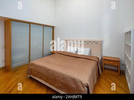 Semplice la luce interna della camera da letto. Letto king size. Pavimento in legno. Guardaroba. Foto Stock