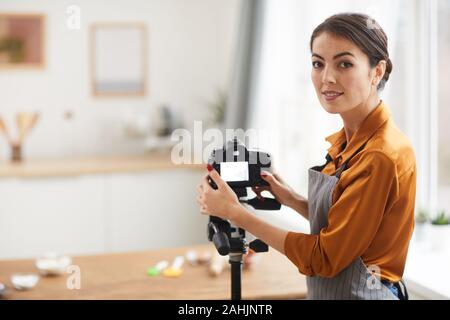 Vita ritratto di donna bella impostazione della fotocamera e sorridente durante le riprese di cottura di tutorial in studio, spazio di copia Foto Stock