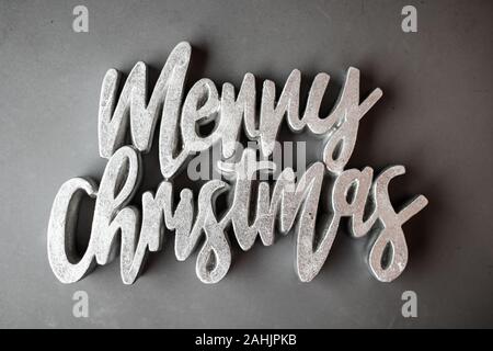 Merry Christmas testo splendenti di segno grigio argento in Font di fantasia su TESTURIZZATO OPACO sfondo grigio Foto Stock