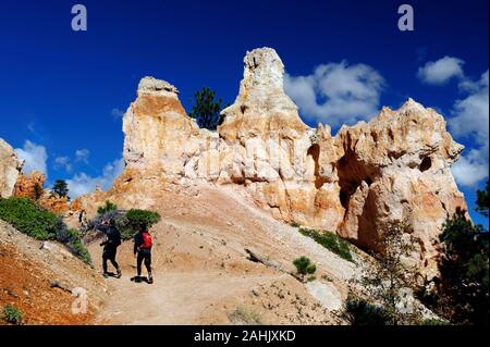 Due escursionisti passando da una formazione di roccia, Parco Nazionale di Bryce Canyon, Utah, Stati Uniti d'America. Foto Stock