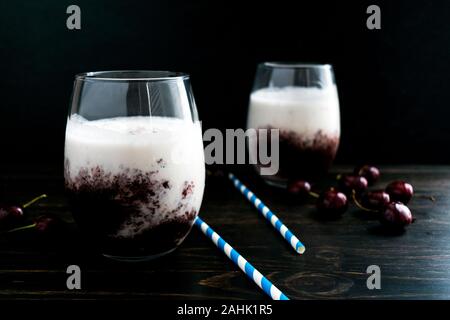 Ciliegia freschi frullati con carta cannucce: Due smoothies fatti con latte di cocco e ciliegia purea in stemless bicchieri di vino Foto Stock