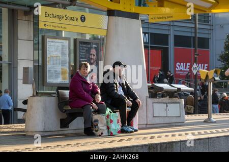 Coppia in attesa a Exchange Square alla fermata del tram e il centro di Manchester Foto Stock