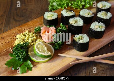 Sushi set - diversi tipi di Maki Sushi e nigiri sushi. Servita su legno scuro tavolo. Foto Stock