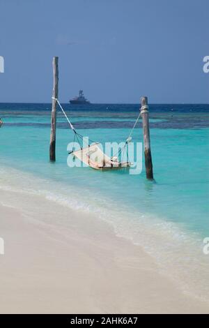 Donna che indossa un bikini e un cappello, rilassante in una amaca in mare a Bandos Island, Maldive, Oceano Indiano Foto Stock