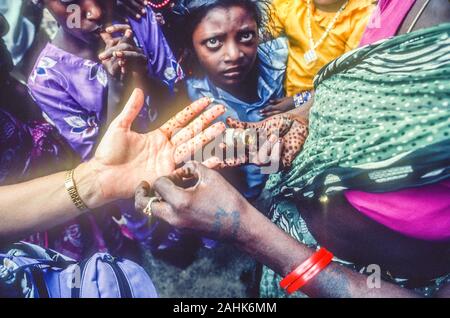 Henna, una temporanea di arte del corpo colorante, essendo applicato ad una femmina del Caucaso in mano a Chennai, in India da una donna indiana. Foto Stock