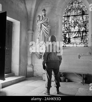 Soldato guardando una statua della Madonna e il bambino in una chiesa, probabilmente in Europa durante la II Guerra Mondiale, fotografia di Toni Frissell, inizio 1940 Foto Stock