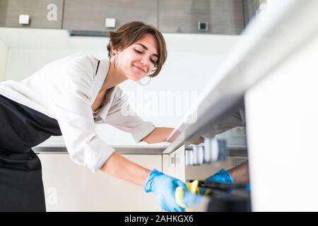 Giovane bella donna pulisce la superficie in cucina Foto Stock