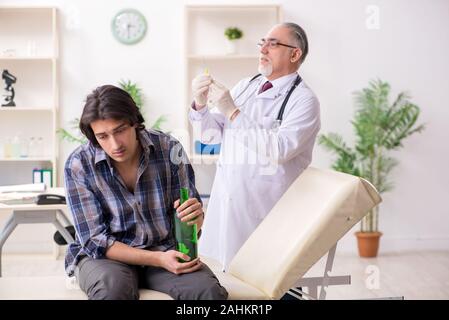 Il giovane maschio gradazione visitando il vecchio medico Foto Stock