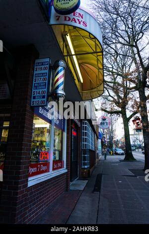 Un locale barbiere con un tradizionale americano del barbiere pole e segno su un mattone shopfront con una tenda. Seattle, Stati Uniti d'America. Foto Stock