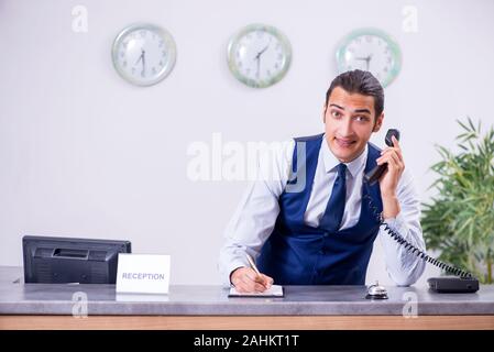 Il giovane addetto al ricevimento presso l'hotel counter Foto Stock