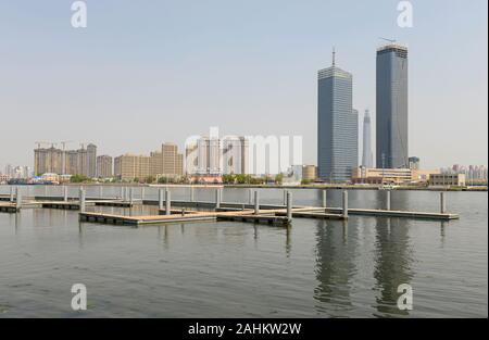 Edifici nuovi e in costruzione di alto livello vicino al fiume Haihe nel quartiere di Binhai, Tianjin, Cina, con il Centro finanziario CTF che sta per essere completato. Foto Stock