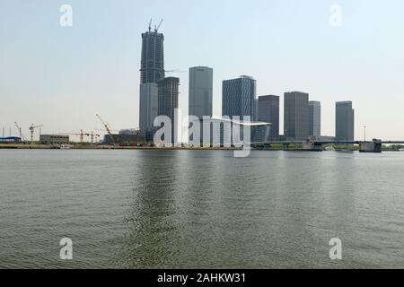 Edifici nuovi e in costruzione di alto livello vicino al fiume Haihe nel quartiere di Binhai, Tianjin, Cina, con il Centro finanziario CTF che sta per essere completato. Foto Stock