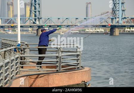 Un uomo getta una rete da pesca nel Fiume Haihe in Binhai distretto, Tianjin City in Cina Foto Stock