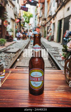 Hanoi una bottiglia di birra su un tavolo nel mezzo delle piste al di fuori di un cafe in Hanoi la famigerata treno Street, Ong 224 Le Duan, nel vecchio quartiere Foto Stock