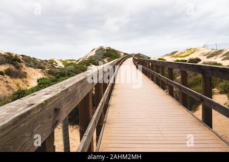 Legno rustico Beach Boardwalk attraverso le dune di sabbia. Oso Flaco Lago Area naturale del parco statale, California Foto Stock