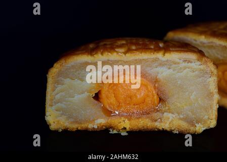 Close-up di un cinese tradizionale torta della luna, tagliata aperta, contro uno sfondo scuro con spazio per il testo Foto Stock