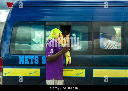 Un uomo keniano vendita di mais abbrustolito ai passeggeri in un bus di matatu, Kenya, Africa orientale Foto Stock