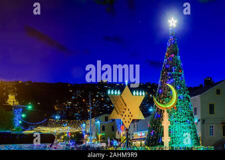 Haifa, Israele - 29 dicembre 2019: la vacanza di vacanze nella colonia tedesca, con un albero di Natale, Hanukkah Menorah, Musulmana Crescent e della BAHA Foto Stock