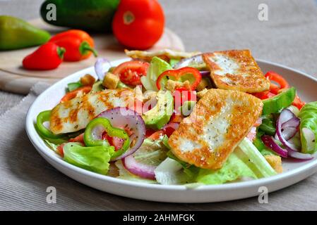 Insalata di formaggio halloumi alla griglia mediorientale con avocado, arance, pomodori ciliegini, cipolla rossa, foglie di barbabietola. . Foto Stock