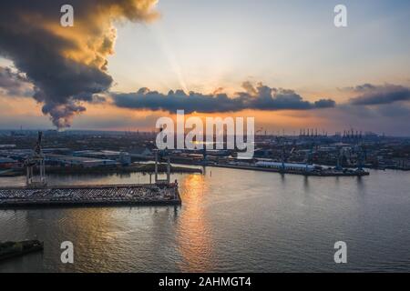 Tramonto con nuvole drammatico al porto di Amburgo con pesanti-gru di sollevamento Foto Stock