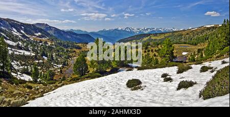 Panorama dalla cima di Madriu-Perafita-Claror Valley con foreste, fiumi e prati in primavera, ghiacciaio nevoso è al primo piano, la catena montuosa di un Foto Stock
