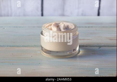 In casa la crema per il viso di oli vegetali in un barattolo di vetro, su una luce sullo sfondo di legno Foto Stock
