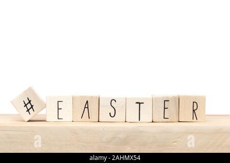 Cubi di legno con un hashtag e la parola Pasqua vicino a sfondo bianco. Social media concept Foto Stock