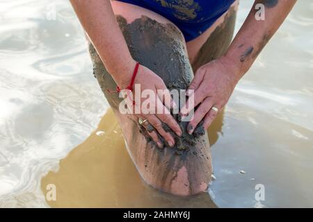 Donna applicando sul suo corpo salato fango curativo nel lago Foto Stock