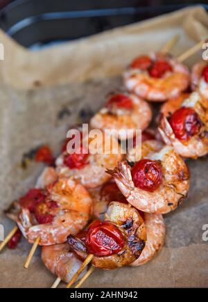 Deliziosi frutti di mare appetitosi spiedini di gamberi infilate su bastoni di legno closeup. Foto Stock