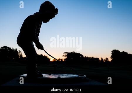 Pinehurst, North Carolina, Stati Uniti d'America. 31 Dic, 2019. Dicembre 31, 2019 - PINEHURST, N.C., STATI UNITI D'AMERICA - Il Putter Boy statua a Pinehurst Resort & Country Club saluta l'ultima alba del 2019. La statua, un simbolo iconico del resort era conosciuta come "La Meridiana Boy' fino agli anni settanta, quando 'il putter Boy' nome catturati su. Per molti anni la statua seduto su una base in cemento tra le due grandi putting greens accanto al clubhouse. Credito: ZUMA Press, Inc./Alamy Live News Foto Stock