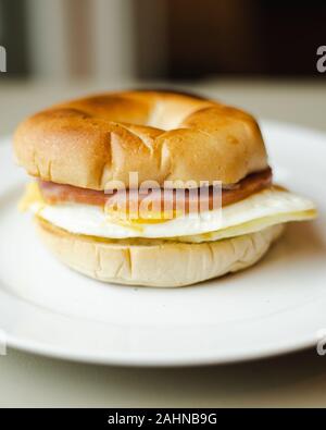 Canadese di uova pancetta bagel colazione vicino a sandwich con sfondo sfocato Foto Stock