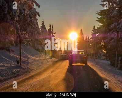 Sun ammaliare gli automobilisti nel paesaggio invernale Foto Stock