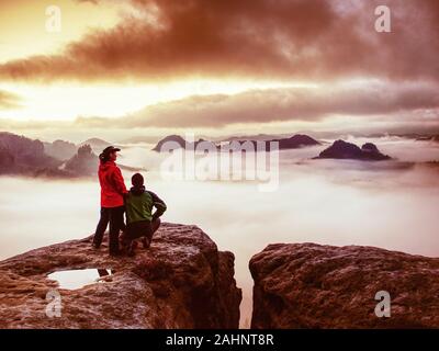 Bella coppia eterosessuale guardando lontano sunrise in nuvole pesanti. La notte oscura nelle montagne di nebbia le estremità. Foto Stock